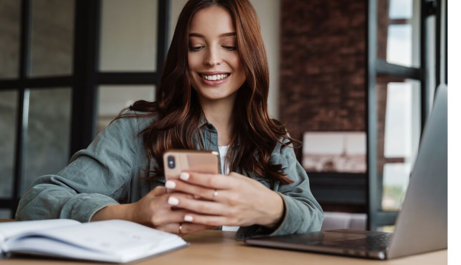 Mulher sorrindo enquanto olha para o smartphone.